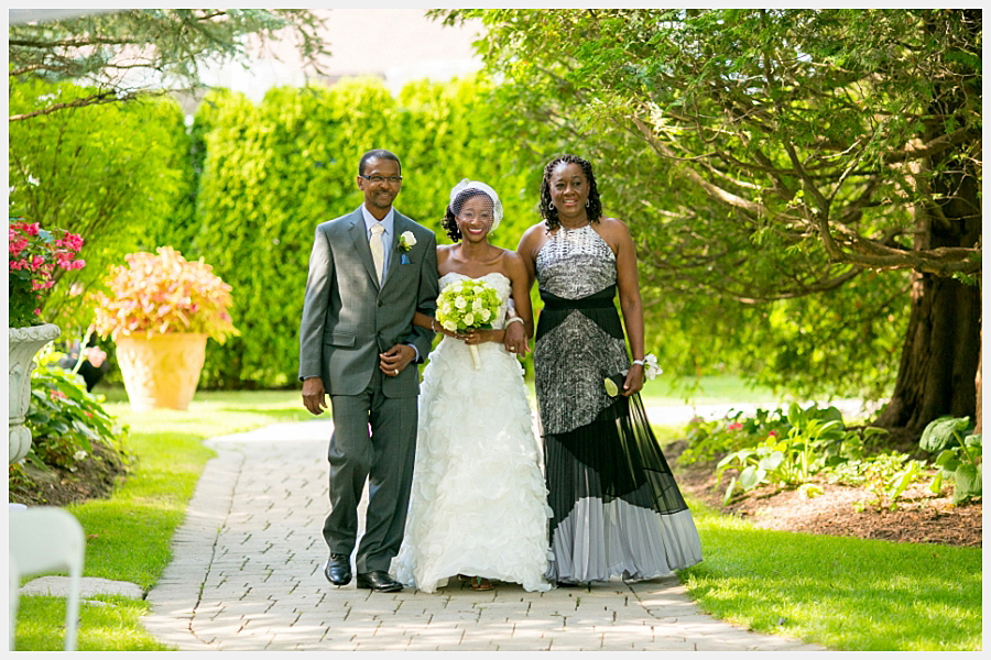 The bride and her parents walk down the aisle at the Royal Ashburn